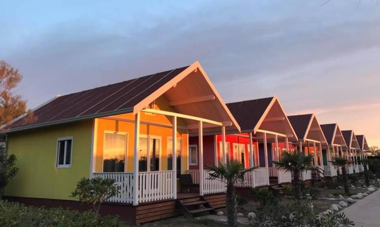 Bunte Bungalows bei Sonnenuntergang, ruhige und entspannte Atmosphäre.