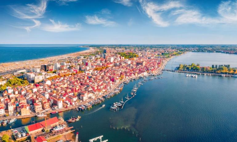 Luftaufnahme einer Küstenstadt mit Meer, Booten und blauem Himmel.