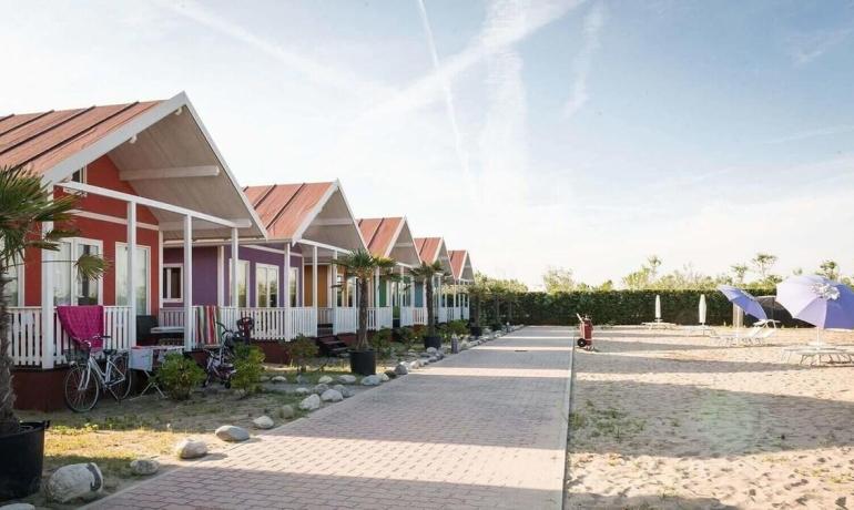 Colorate casette sulla spiaggia, atmosfera serena e rilassante, ombrelloni e biciclette.