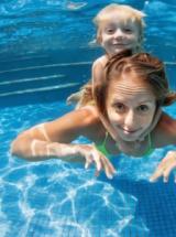 Donna e bambino giocano felici sott'acqua in piscina.