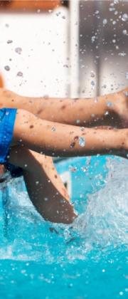 Gambe di bambino che giocano in piscina, spruzzi d'acqua ovunque.