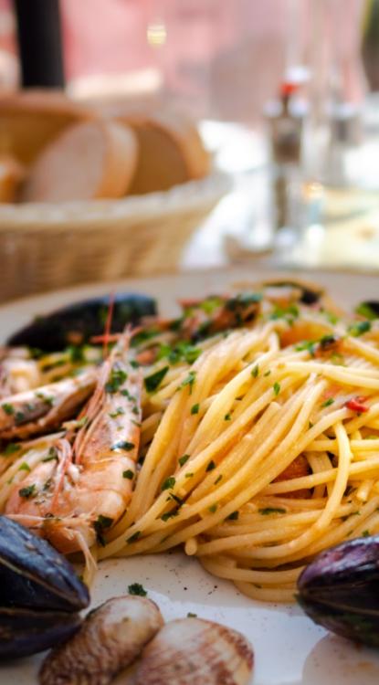 Spaghetti ai frutti di mare con cozze, gamberi e prezzemolo fresco, serviti con pane.