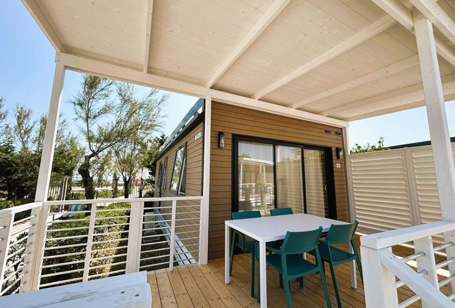 Gemütliche Terrasse mit Tisch, Stühlen und Blick auf Bäume und klaren Himmel.