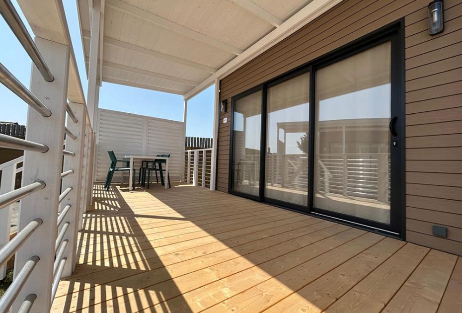 Geräumige Holzveranda, strahlende Sonne, entspannte Atmosphäre.