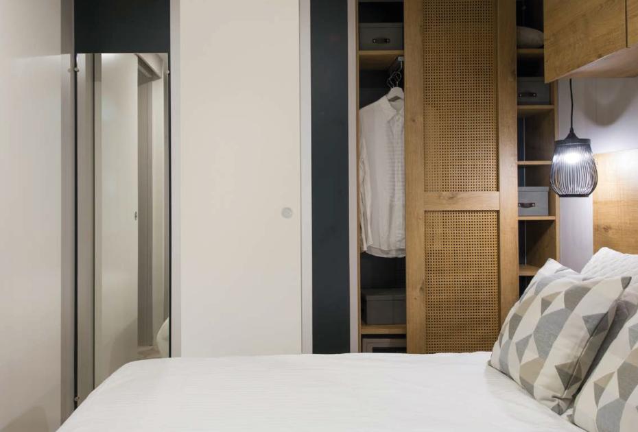 Camera da letto moderna con armadio a vista e lampada sospesa.