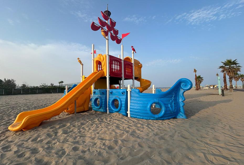 Bunter schiffsförmiger Rutsche auf einem sonnigen Strand.