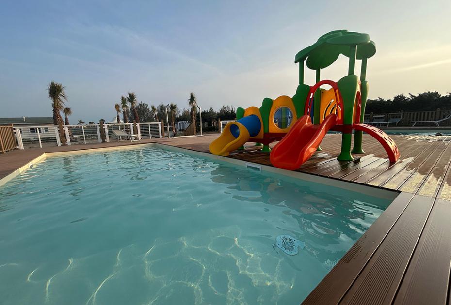 Pool mit buntem Rutsche, Palmen und klarem Himmel: Urlaubs- und Entspannungsstimmung.