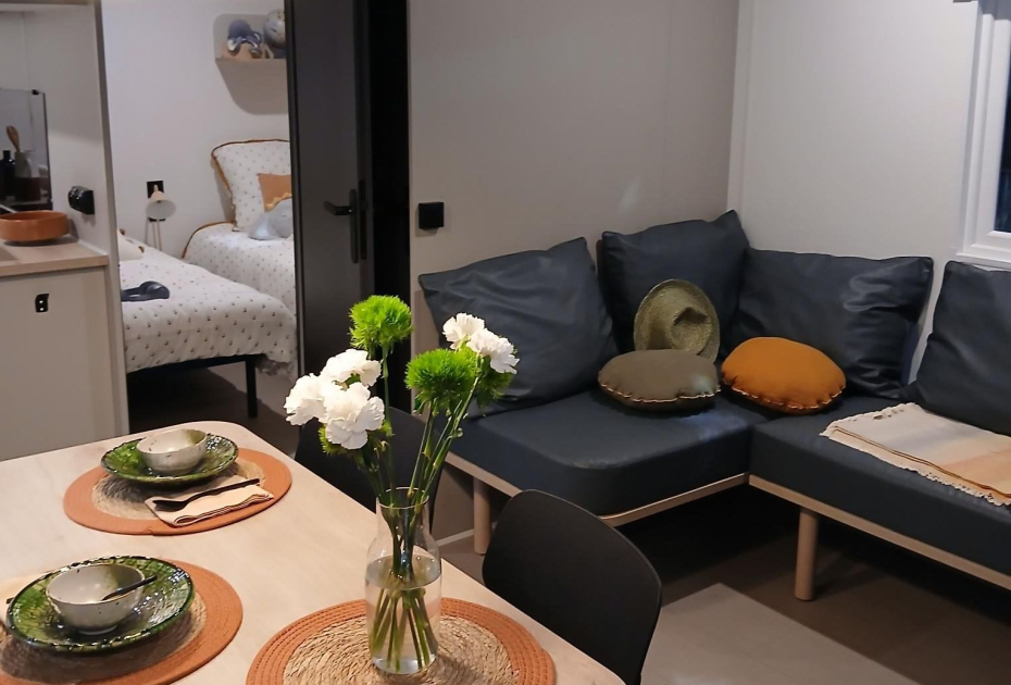 Soggiorno moderno con tavolo da pranzo, divano angolare e decorazioni eleganti.