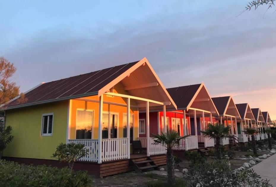 Bungalow colorati al tramonto, con palme e giardini, in un ambiente sereno.